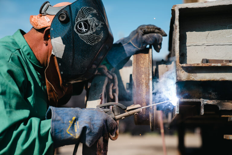 Skilled welder performing precise ship repair work on a piece of iron, showcasing Hendry Marine Industries' expertise in maritime services in Tampa, FL.