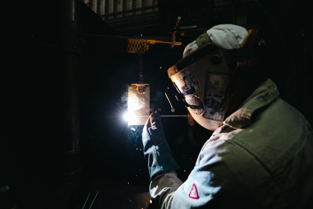 Welder in action, skillfully welding metal with sparks flying, showcasing the hands-on training and expertise developed at the A.W. Hendry Training Center.
